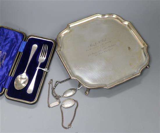 A shaped square silver presentation salver, a cased two-piece Christening set, two silver identity bracelets and a plated bracelet